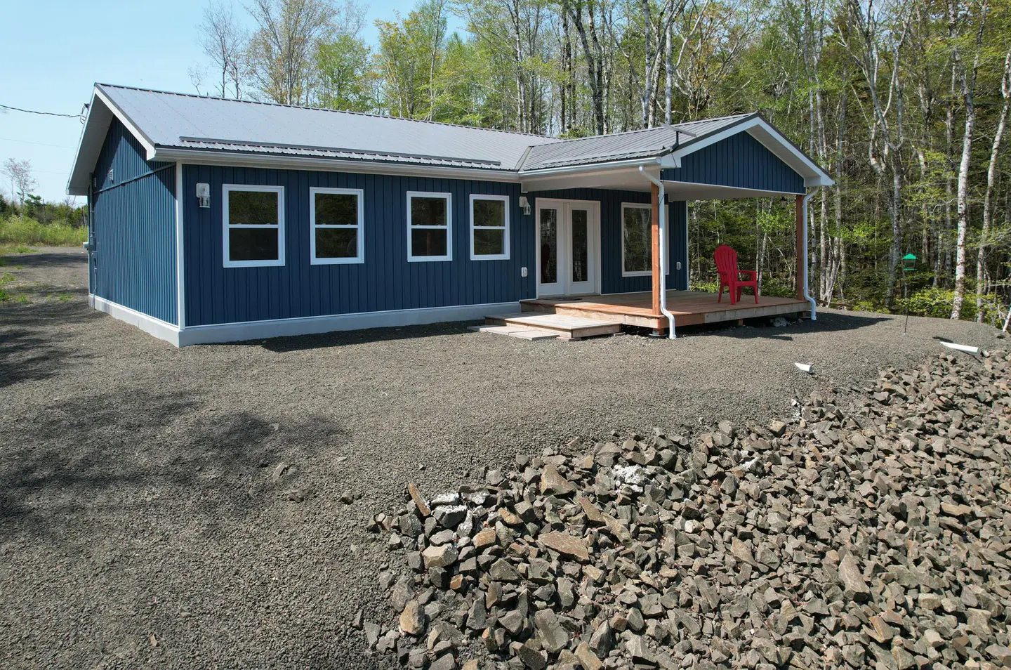 A blue house with a metal roof and a red chair on the porch.