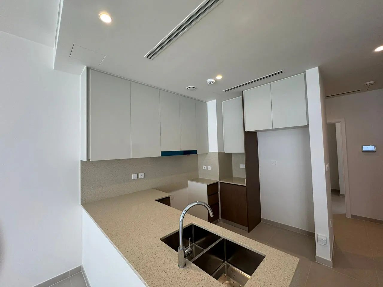 A modern kitchen with white cabinets, a speckled countertop, and a stainless steel sink.