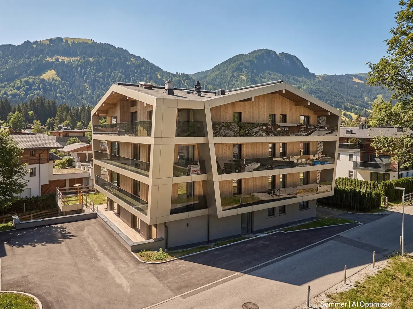Modern apartment building with wood and beige siding, glass balconies, and mountain views on a sunny day.