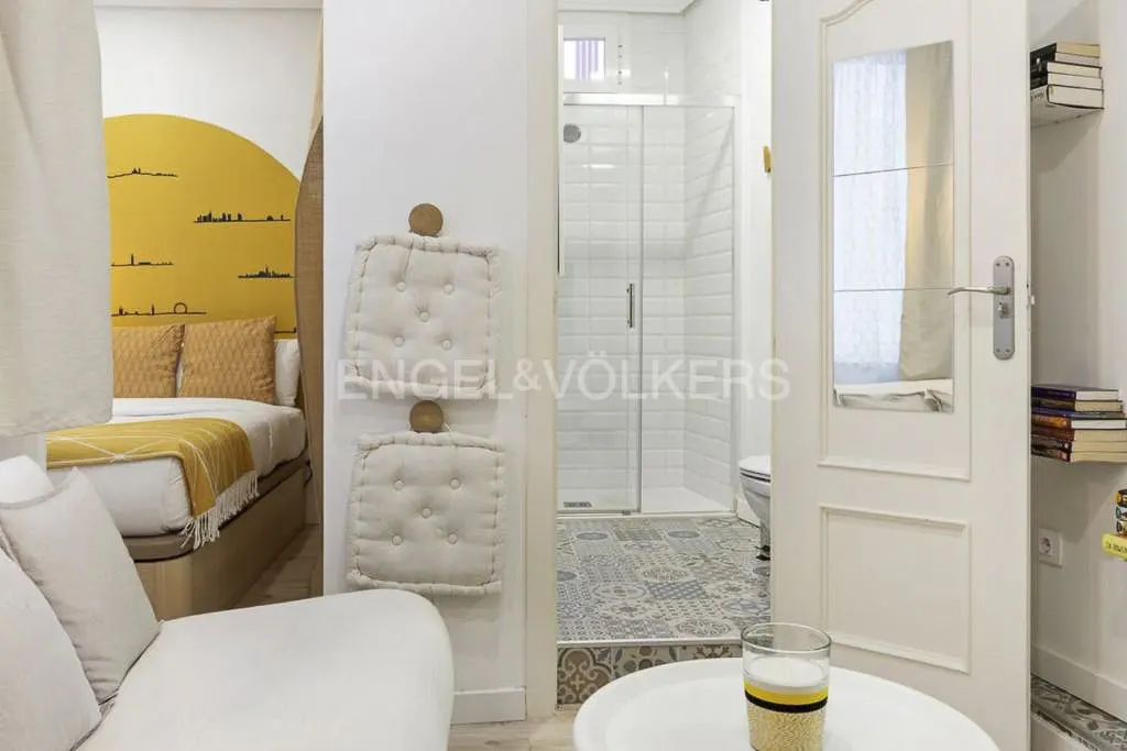 Interior view of a bedroom, bathroom, and living room with white walls and modern decor.