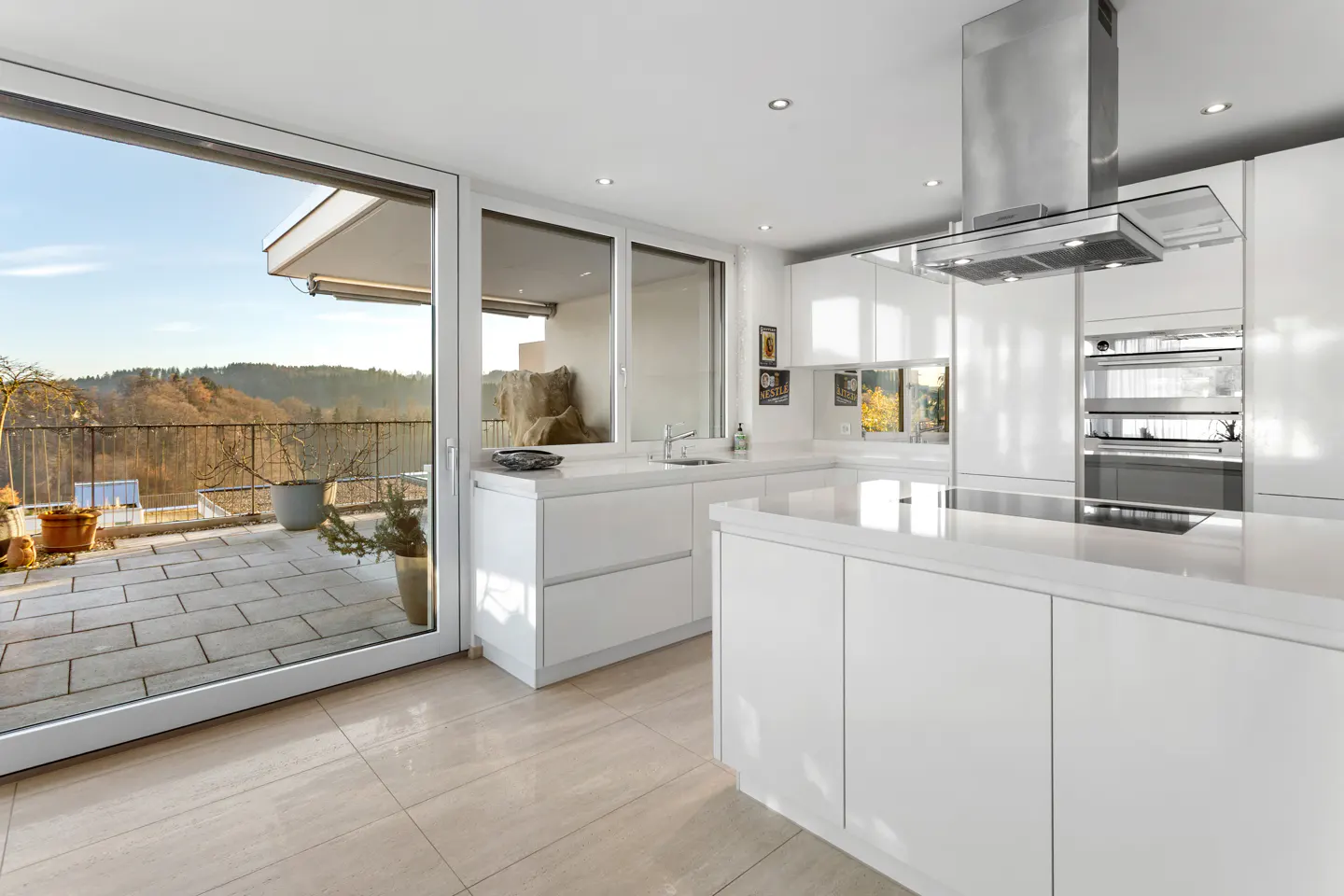 Bright, modern kitchen with white cabinets, stainless steel appliances, and a large sliding glass door to a patio with a scenic view.