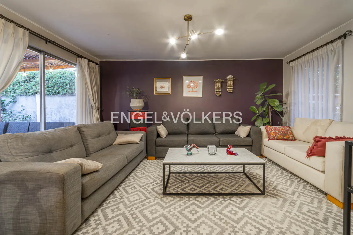 Living room with gray and white sofas, a marble coffee table, and a dark purple accent wall with framed art.