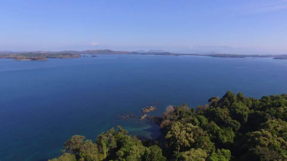 Aerial view of a blue ocean with green, tree-covered islands under a clear blue sky.
