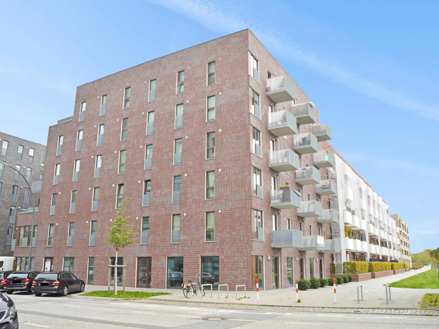 Exterior view of a modern brick apartment building with balconies under a blue sky.