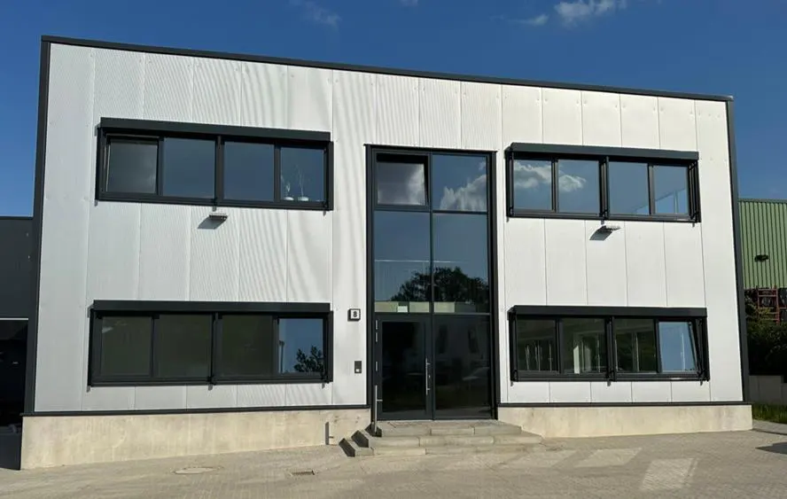 Two-story white building with black trim and large windows under a blue sky.