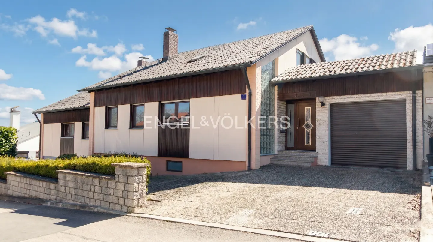 Two-story house with a brown garage door, a brown front door, and a gray roof on a sunny day.