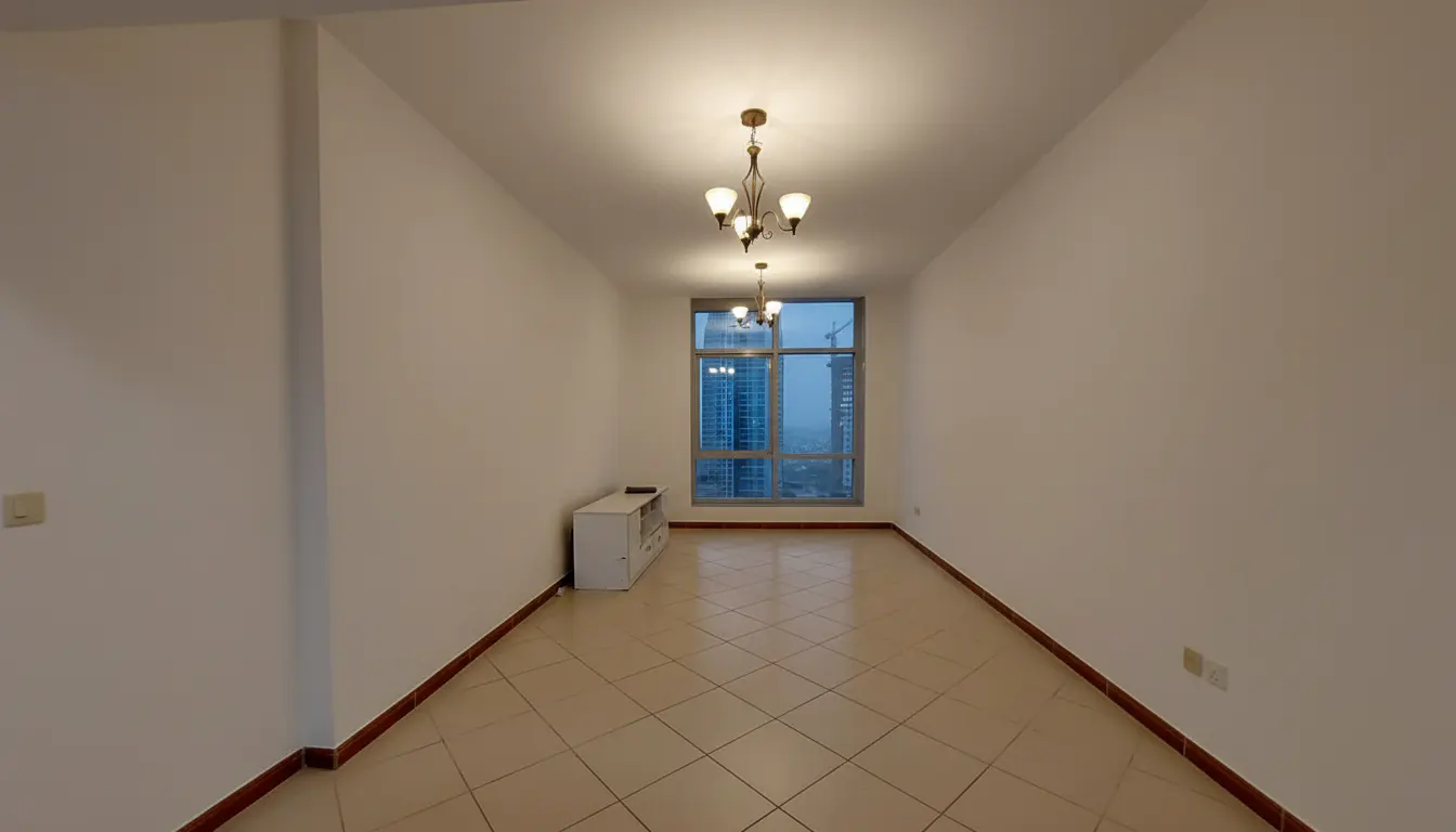 Empty room with beige tile floor, white walls, and a chandelier. A window shows a city view.