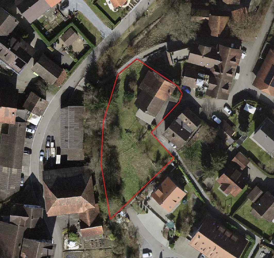 Aerial view of a property outlined in red, surrounded by houses with brown roofs and green trees.