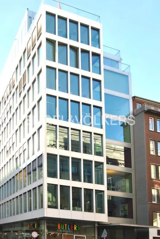 Exterior of a modern white building with many windows, reflecting the sky. "Butlers" store is on the ground floor.