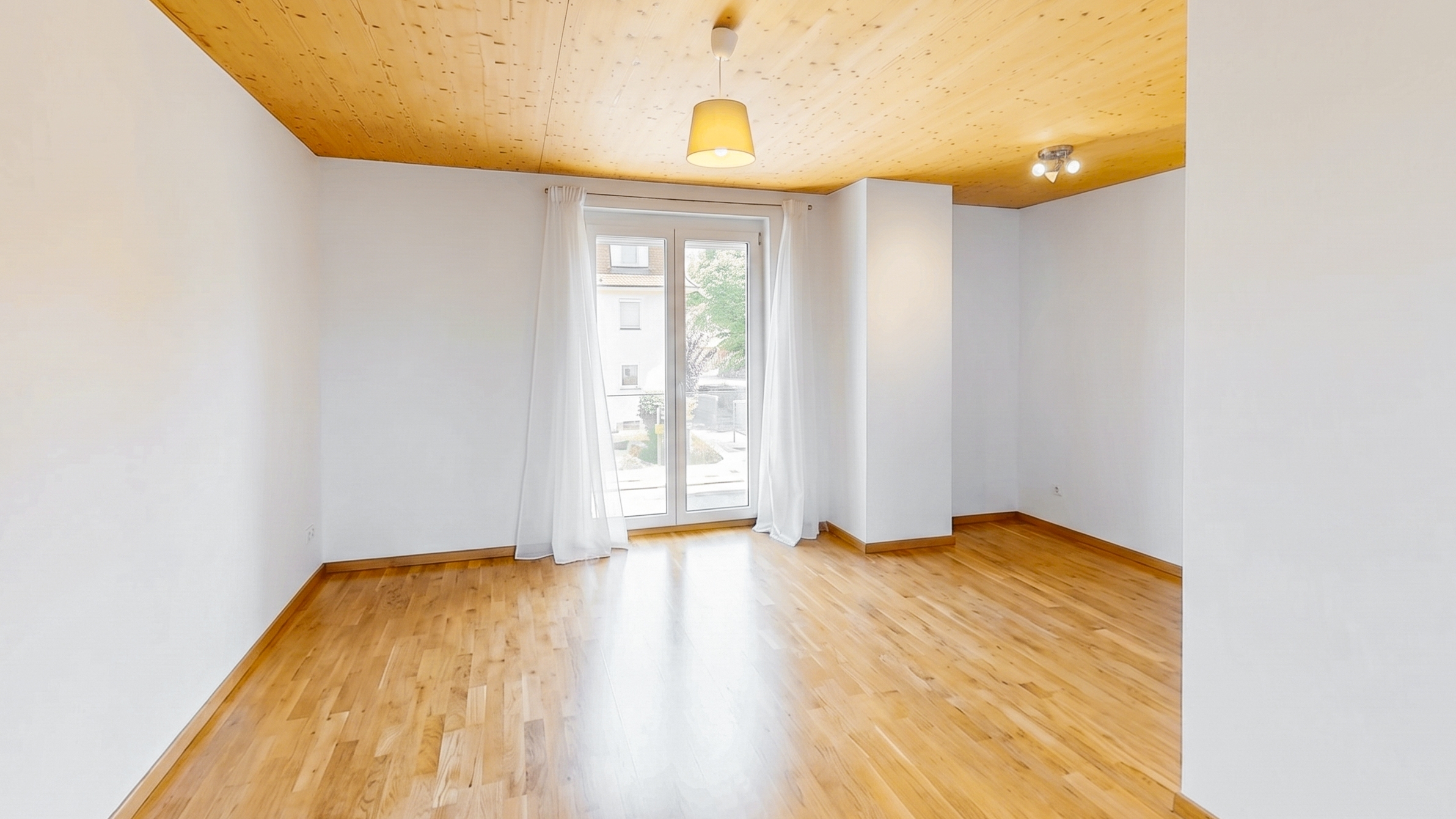 Empty room with white walls, light wood flooring, a matching wood ceiling, and glass doors with white curtains.