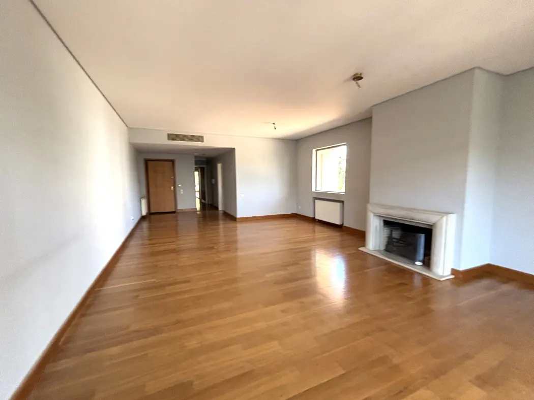 Unfurnished living room with hardwood floors, light gray walls, a marble fireplace, and a window.