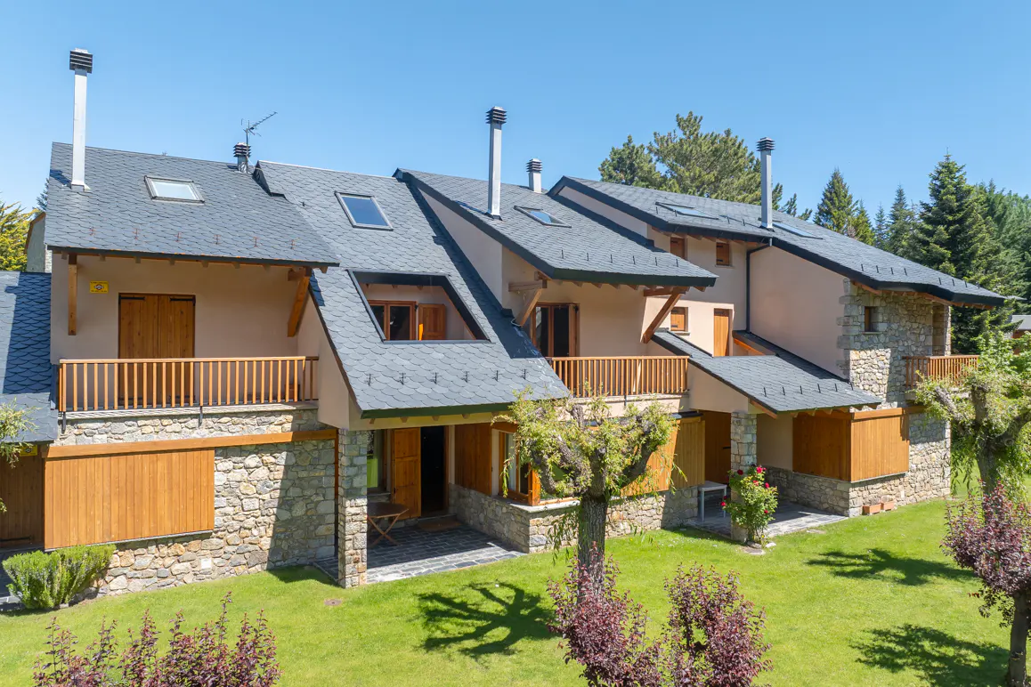 Exterior view of three-story townhouses with stone and stucco facades, slate roofs, and green lawn.