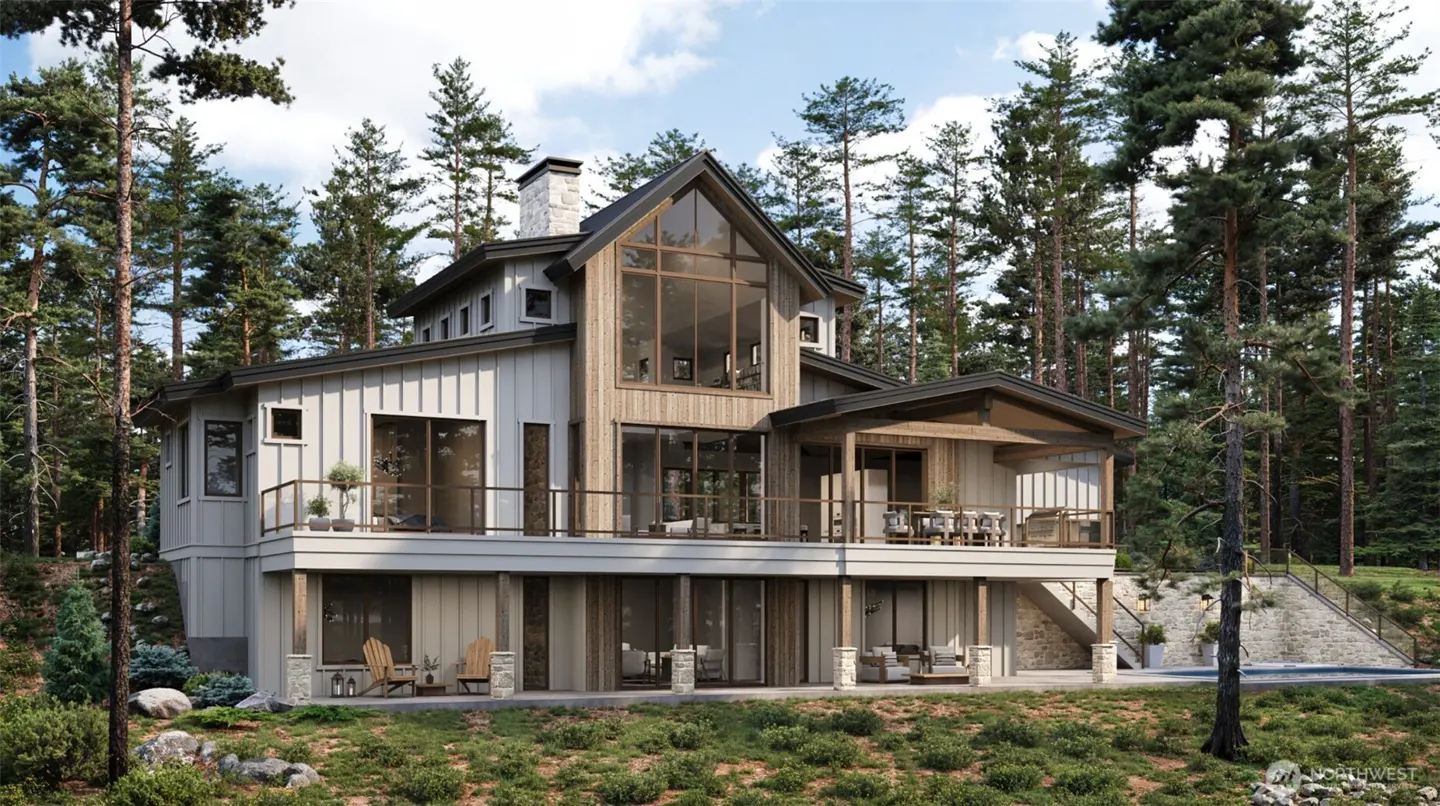 Two-story house with a stone chimney and large windows, surrounded by tall trees. The house has a deck with outdoor furniture.