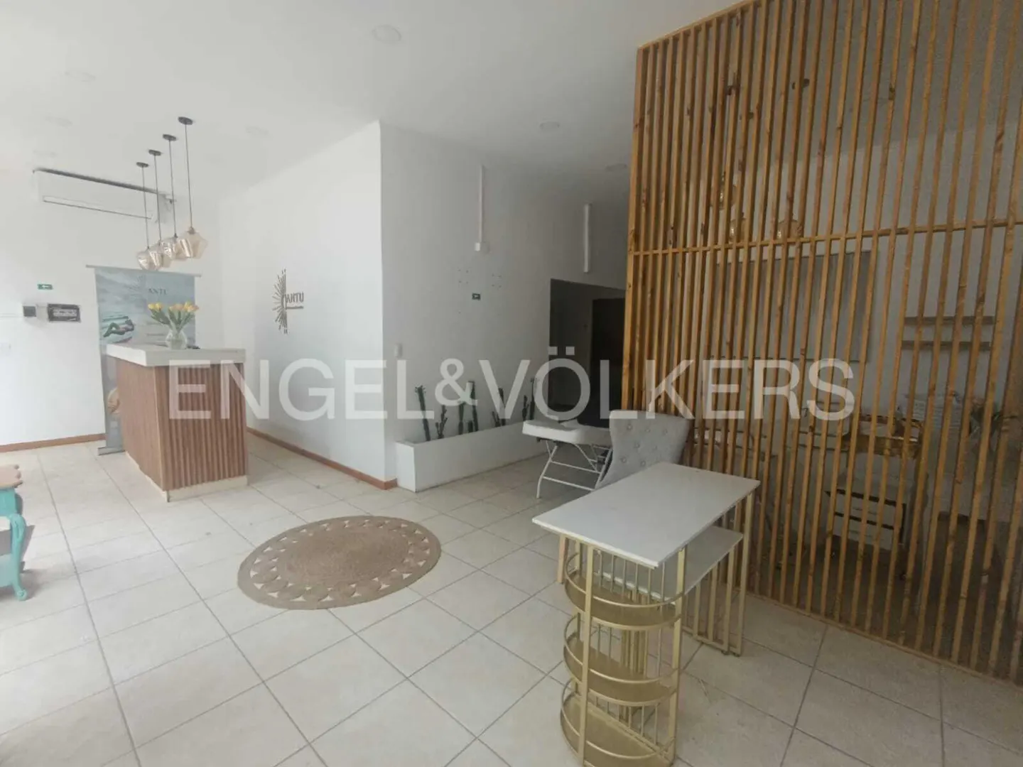 A bright real estate office with a reception desk, wood screen, and Engel & Völkers logo.