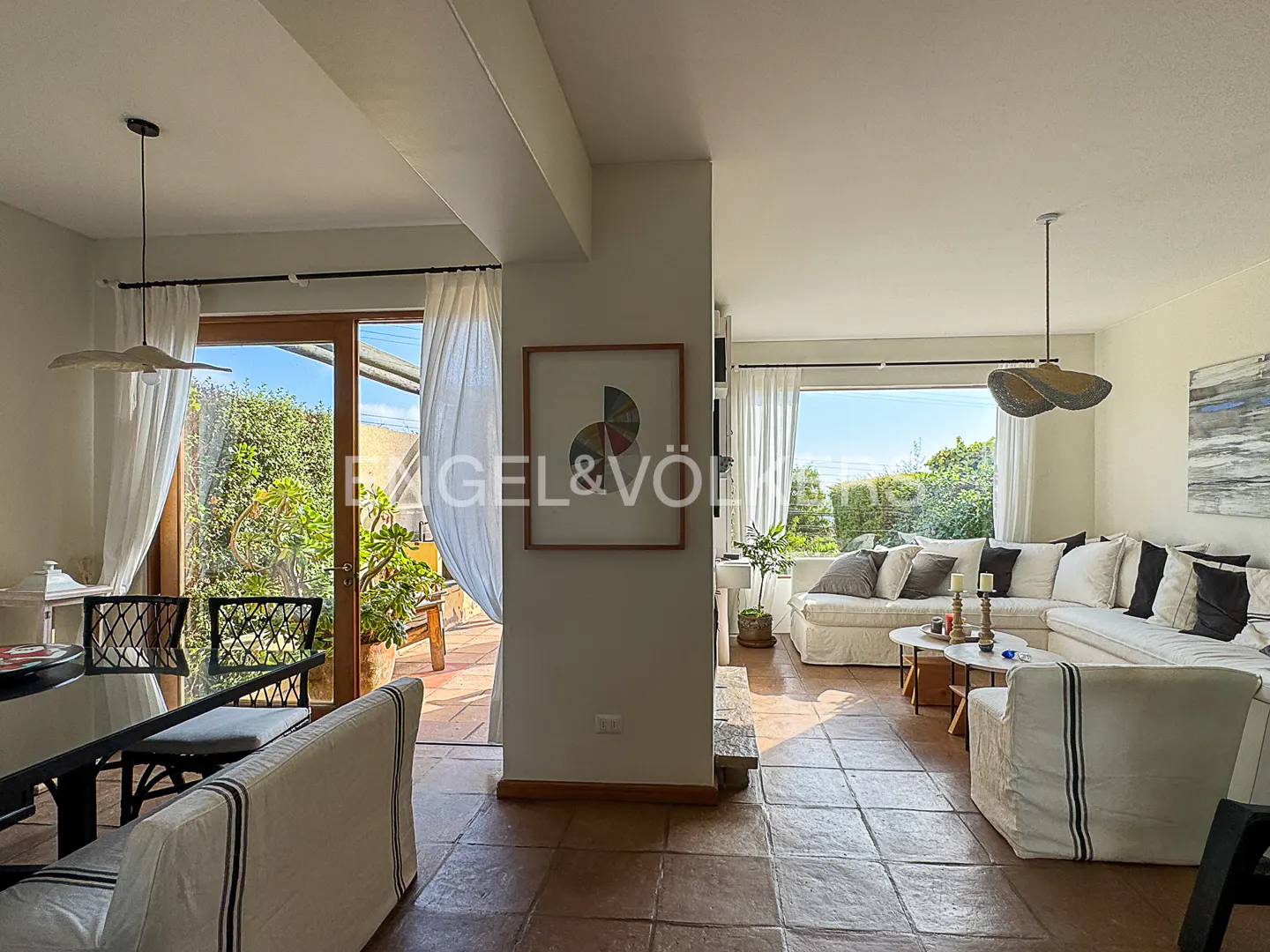 Open-concept living space with dining table, white sofa, and outdoor patio view.