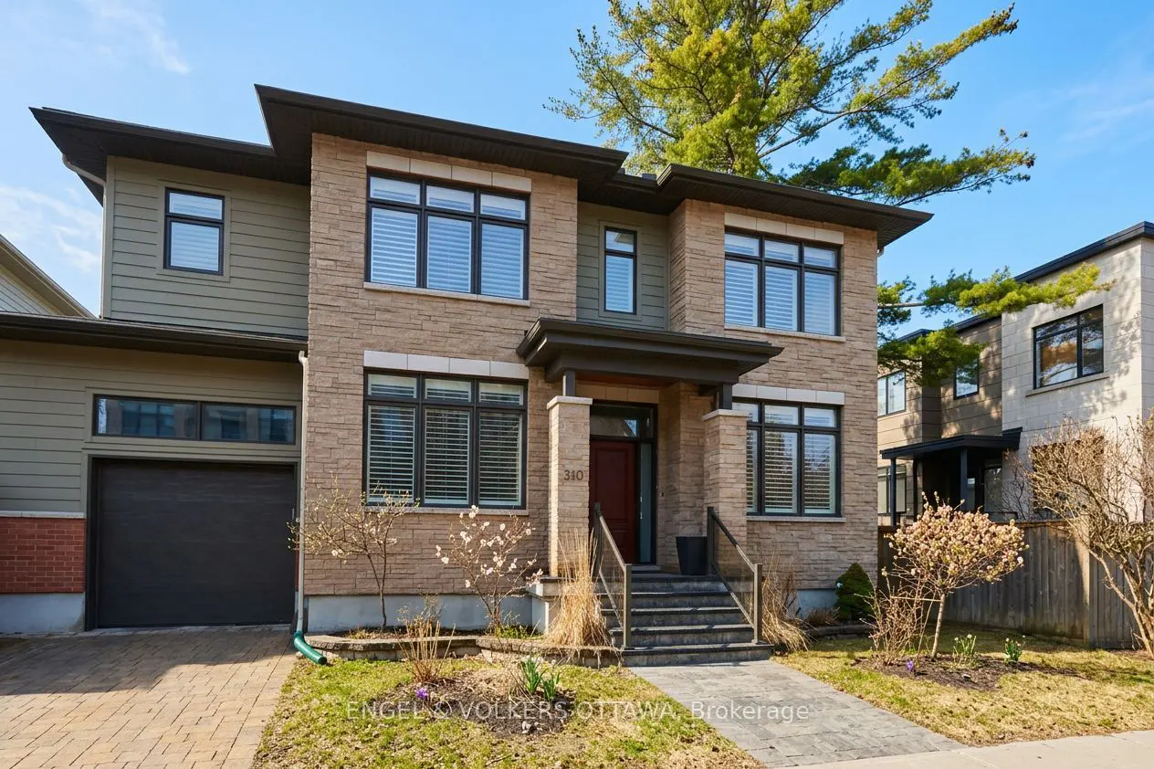 Two-story house with stone and olive green siding, black trim, and a red door. Steps lead to the entrance. Blue sky background.