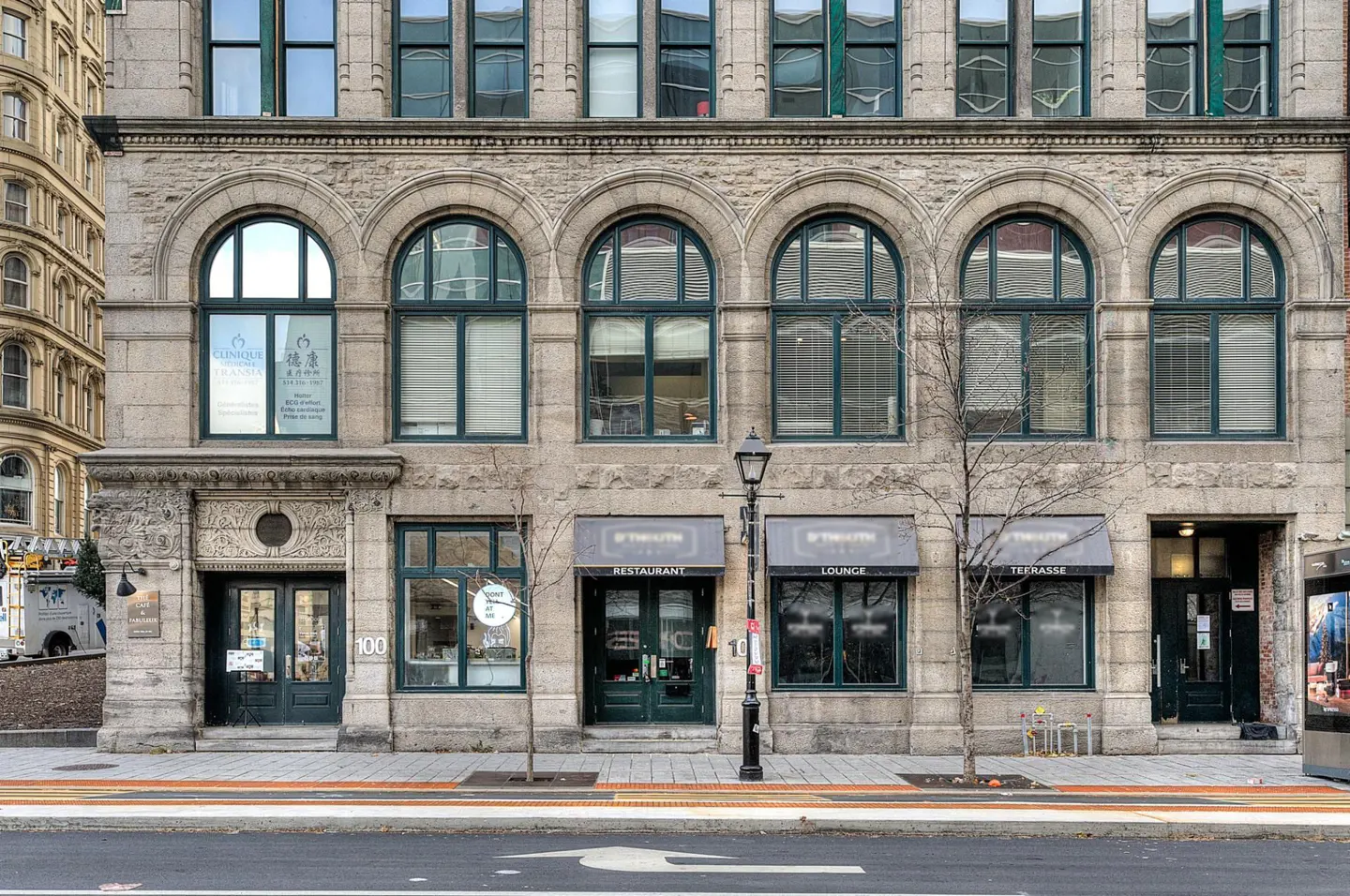 A three-story stone building with arched windows and green trim, housing a restaurant, lounge, and terrace.