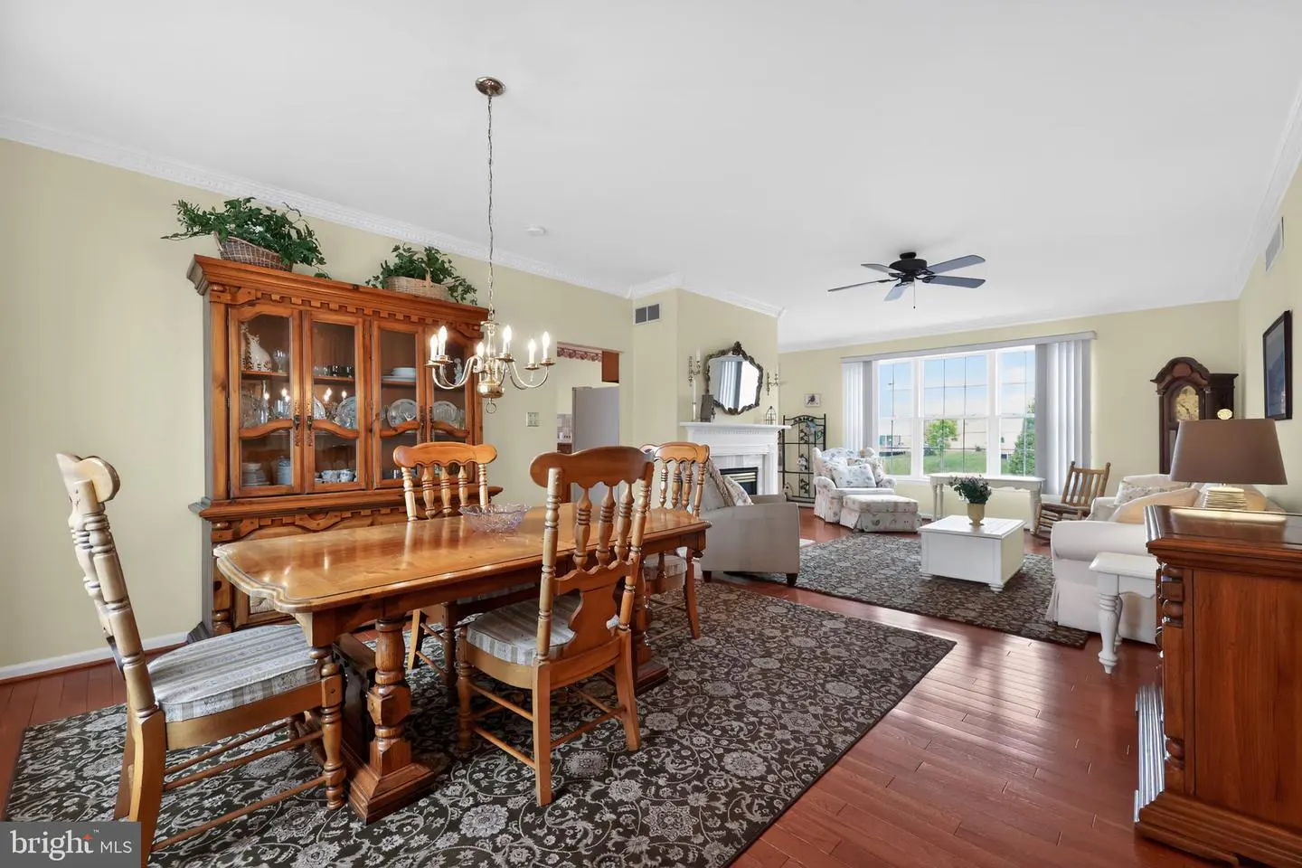 Open-concept home with wood floors, a dining table with chairs, and a living room with a fireplace and white sofas.