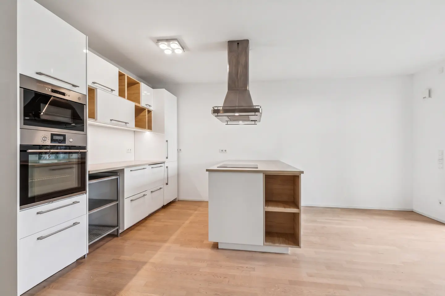 A modern kitchen with white cabinets, stainless steel appliances, and a central island with a range hood.