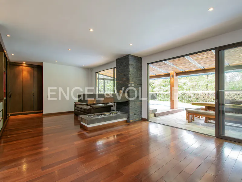 A modern living room with hardwood floors, a stone fireplace, and sliding glass doors to an outdoor patio.