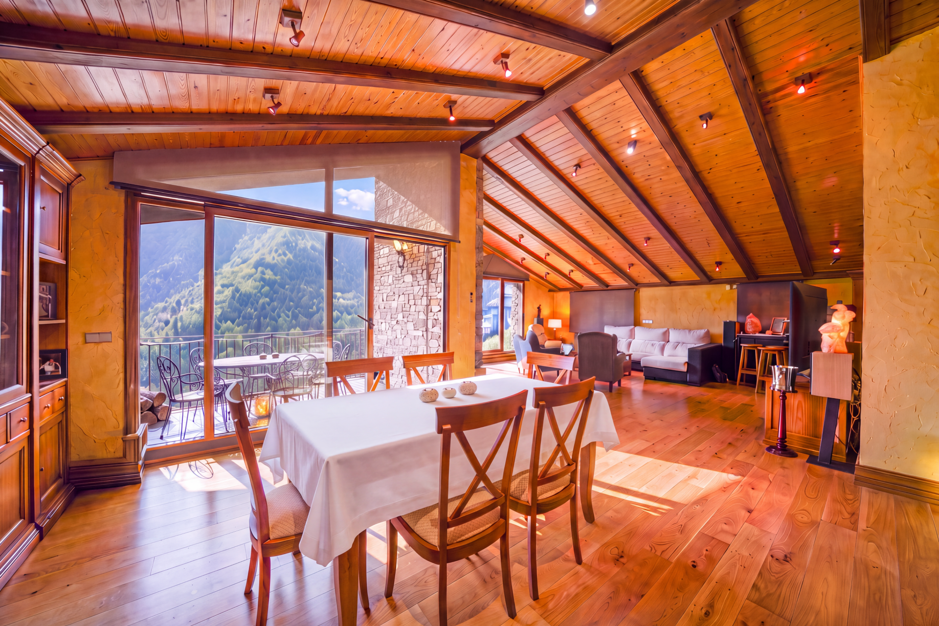 Rustic dining room with wood-beamed ceiling, white-clothed table, and large windows overlooking a mountain landscape. [AI-generated text]