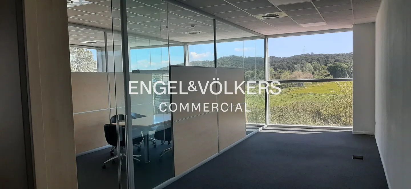 Engel & Völkers commercial office with glass walls, black carpet, and a view of green hills.
