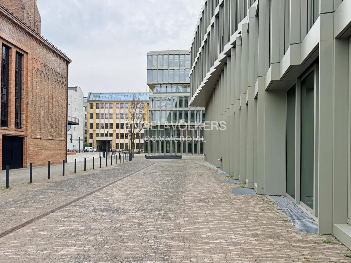 Exterior view of modern office buildings with brick and gray facades, and a cobblestone walkway.