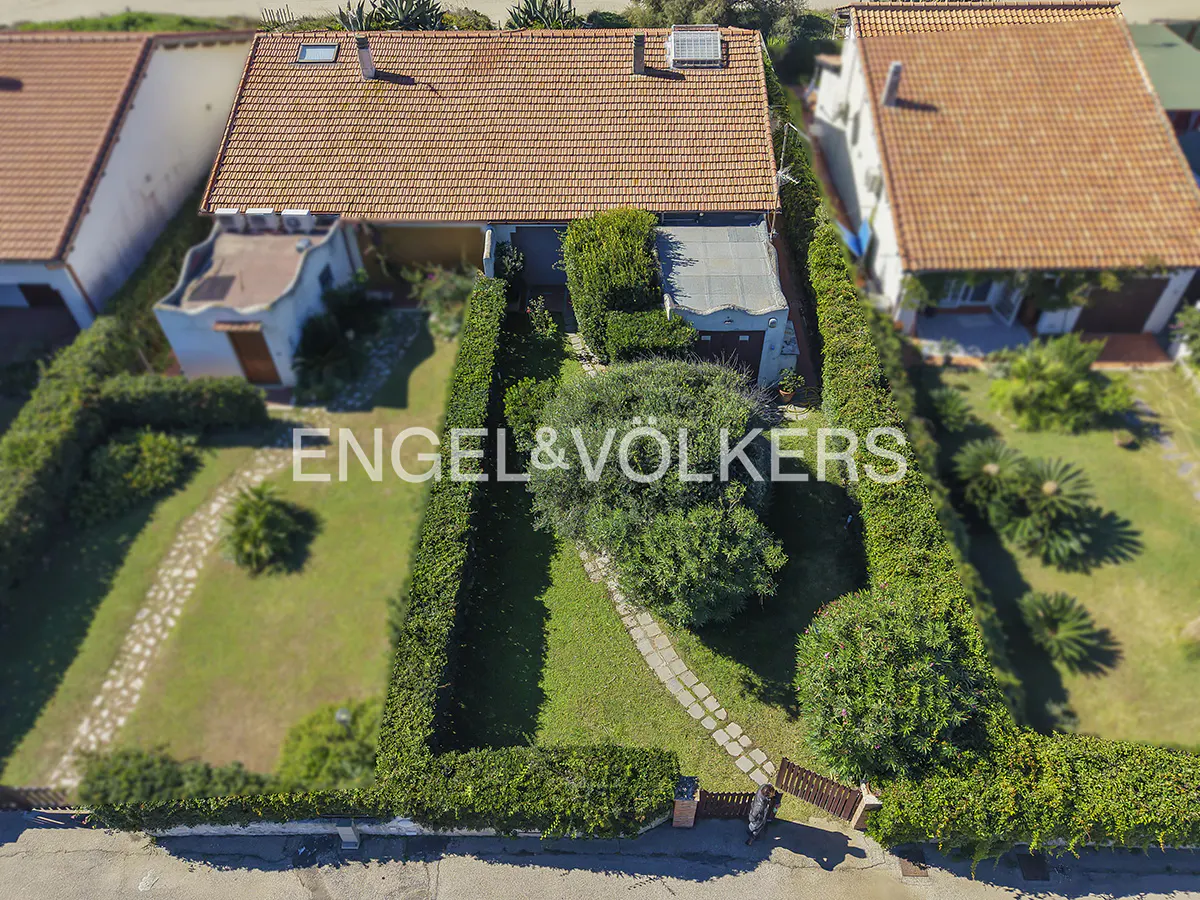 Aerial view of a single-family home with a red tile roof, surrounded by green hedges and lawn. An Engel & Völkers logo is superimposed on the image.