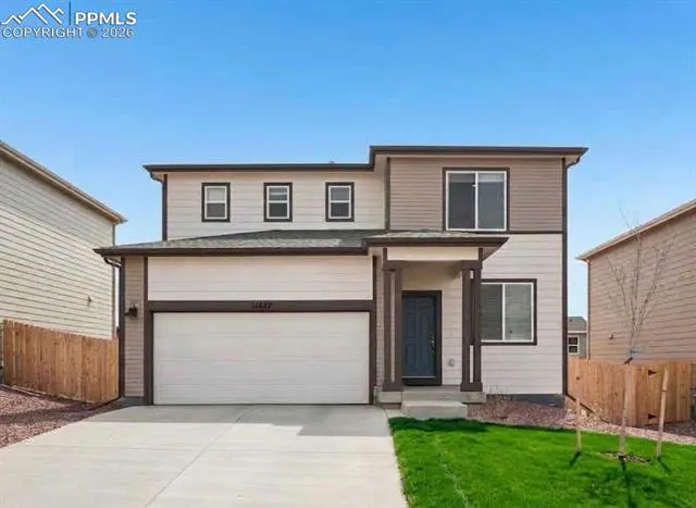 Two-story house with a white garage door, a blue front door, and a green lawn.