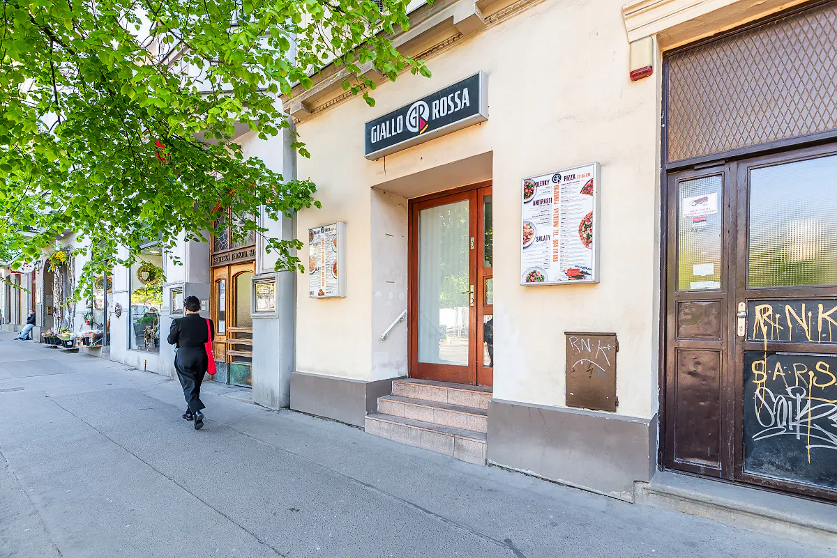 Street view of Giallo Rossa restaurant with a person walking towards another restaurant. The building is cream-colored with brown doors.