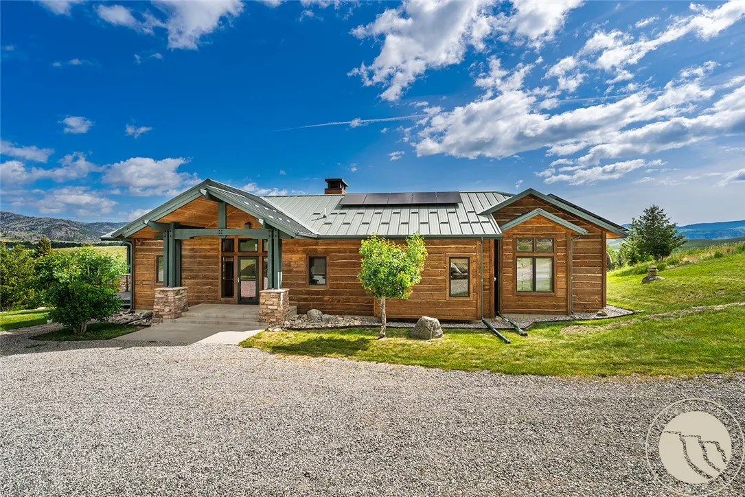 Exterior of a wood cabin home with a metal roof and solar panels on a sunny day.