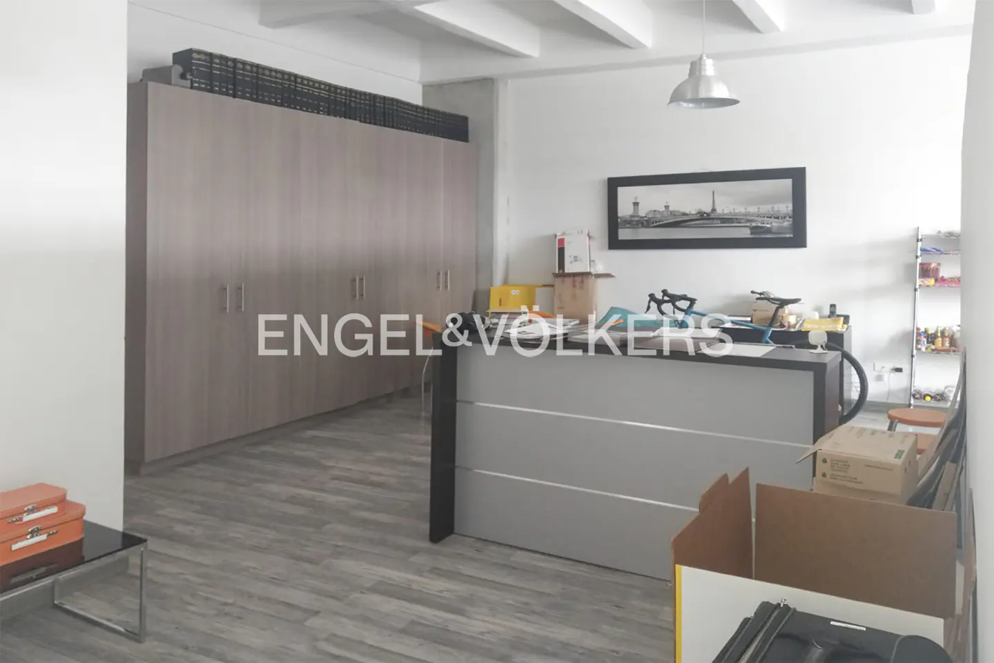 Real estate office interior with a large gray cabinet, a gray reception desk, and the Engel & Volkers logo.