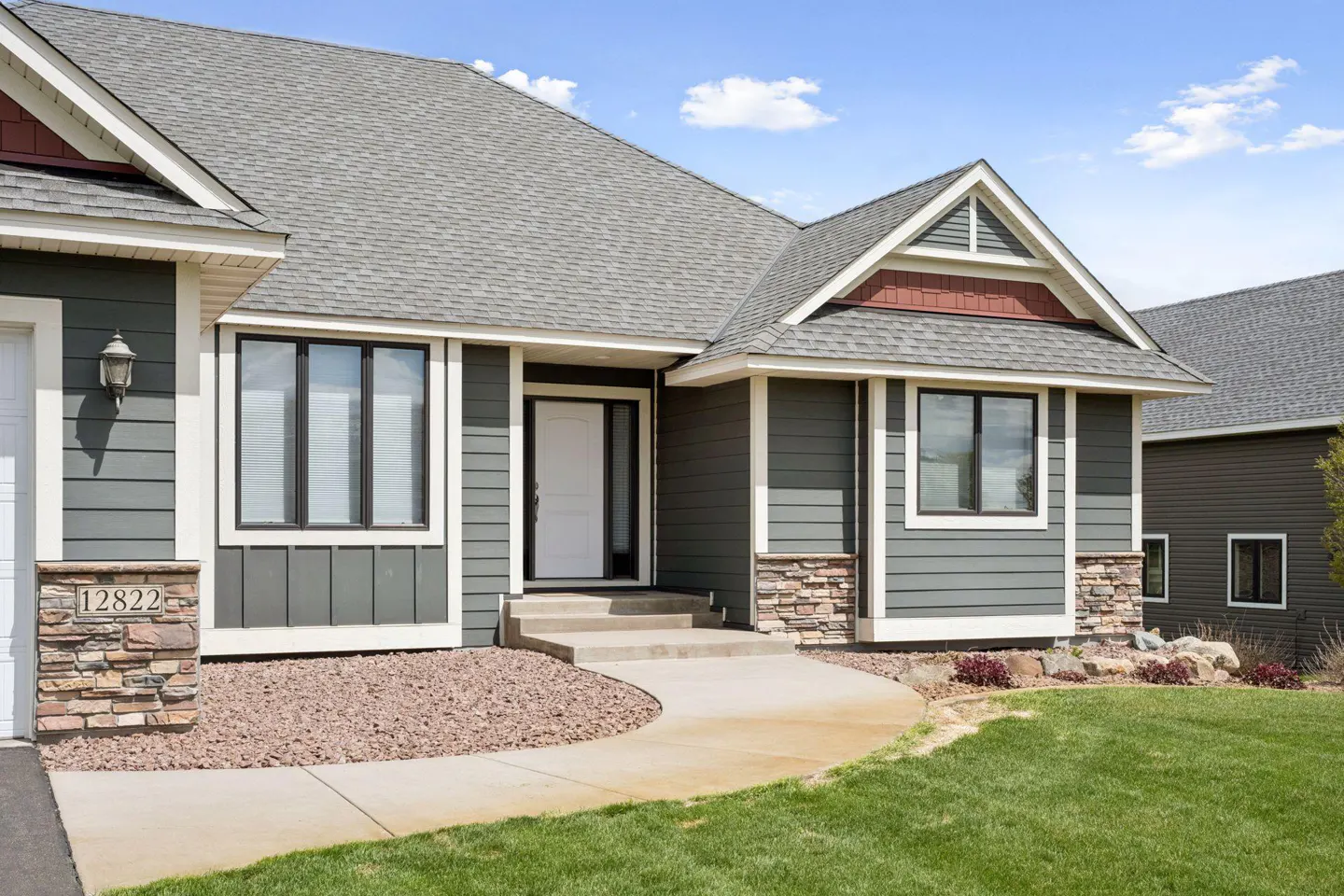 Exterior of a gray house with a white door, gray roof, and a curved sidewalk leading to the entrance.