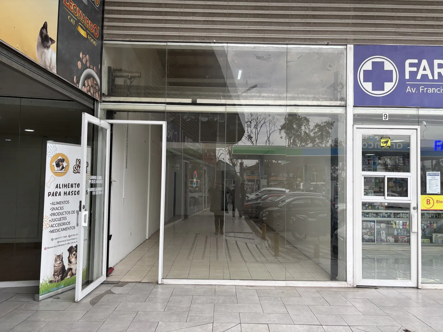 Storefront with glass windows and doors, next to a pet food store and a pharmacy.
