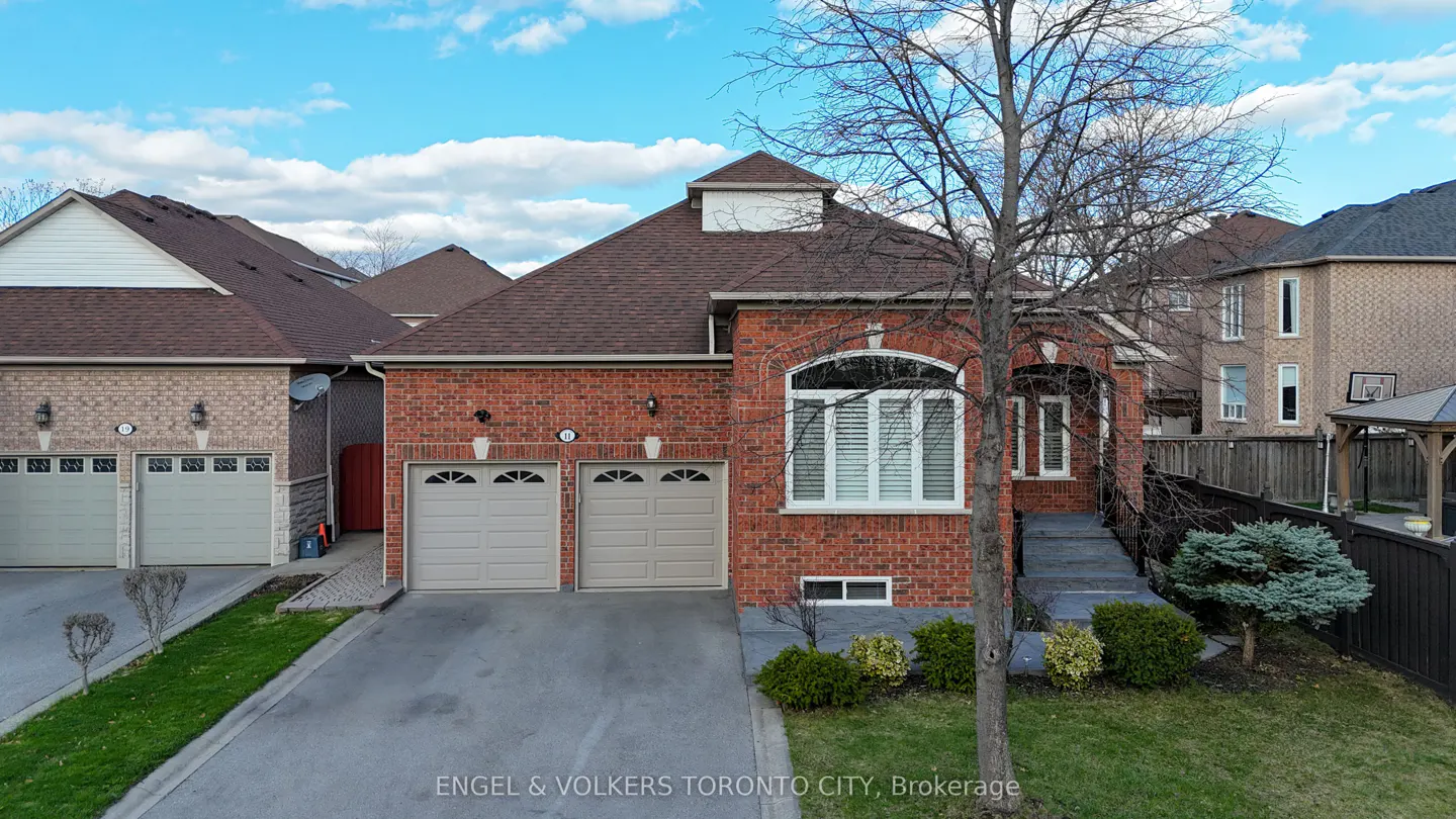 A red brick house with a brown roof, two-car garage, and a tree in the front yard.