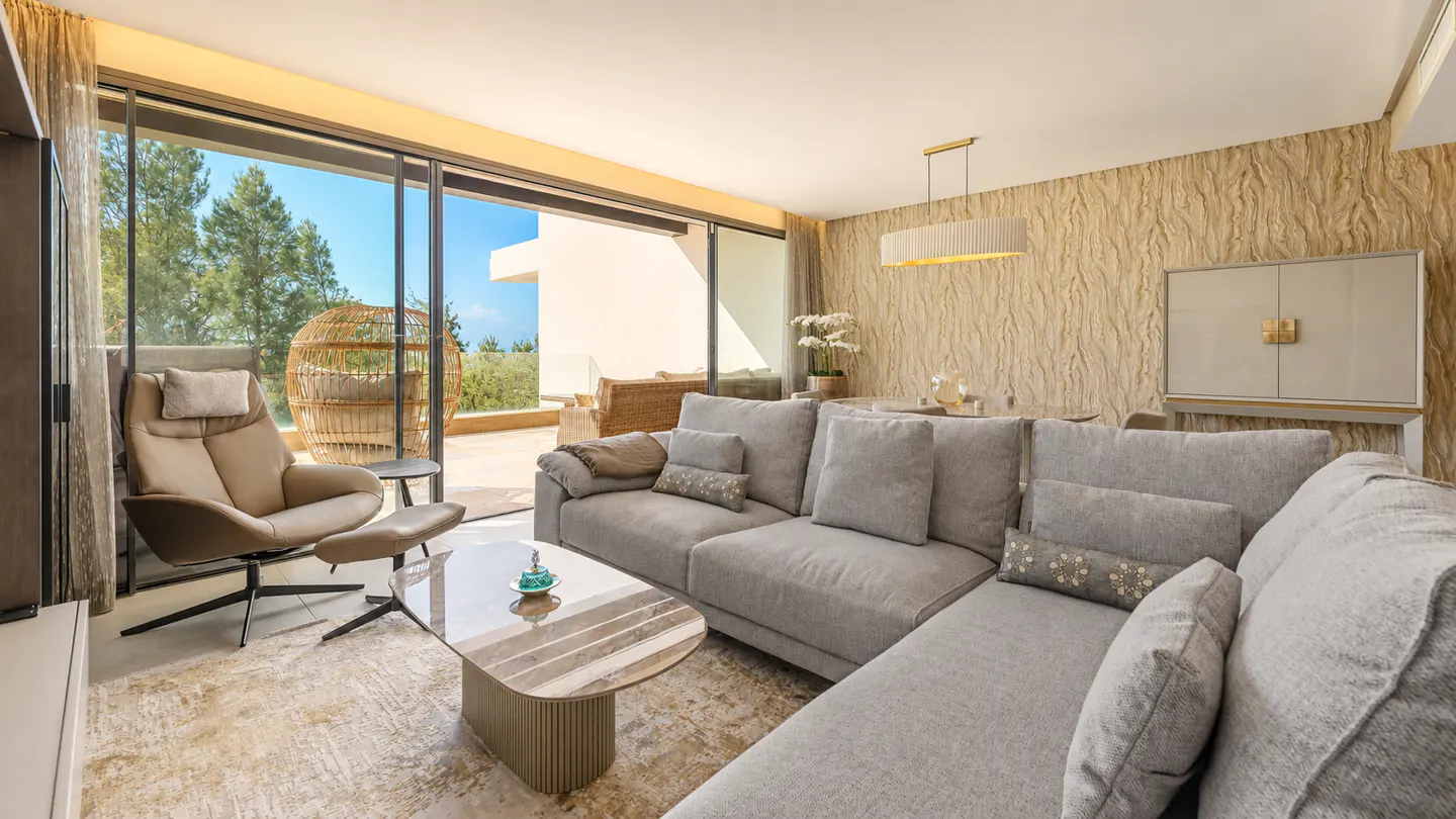 A modern living room with a gray sectional sofa, tan chair, and sliding glass doors to a patio.