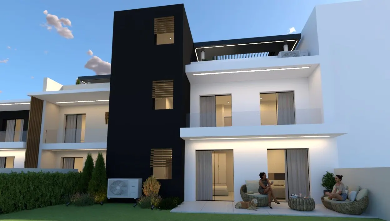 Modern townhouse with black and white exterior, green lawn, and two women sitting on patio furniture.