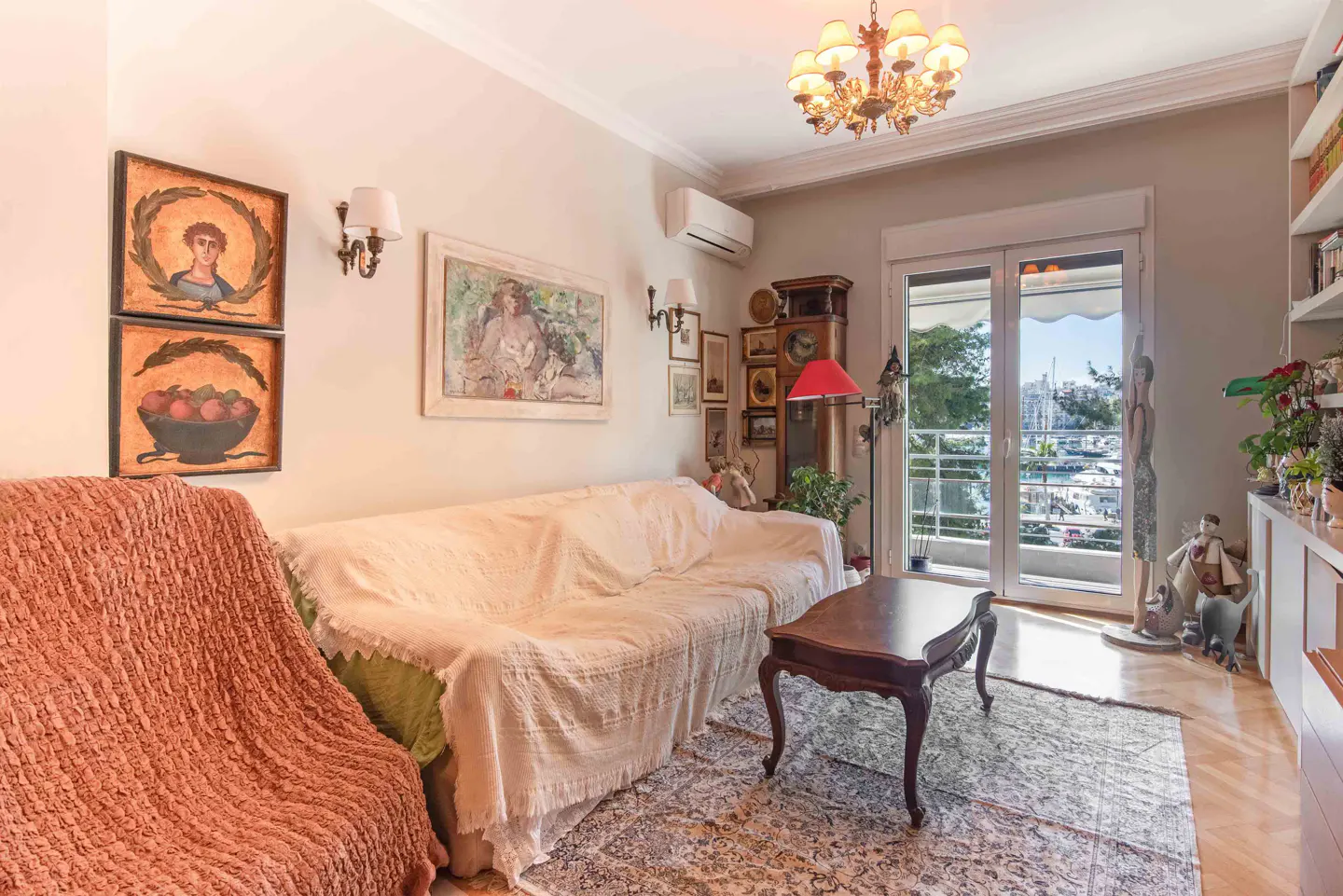 Cozy living room with a white sofa, wooden coffee table, patterned rug, and balcony doors overlooking a marina.
