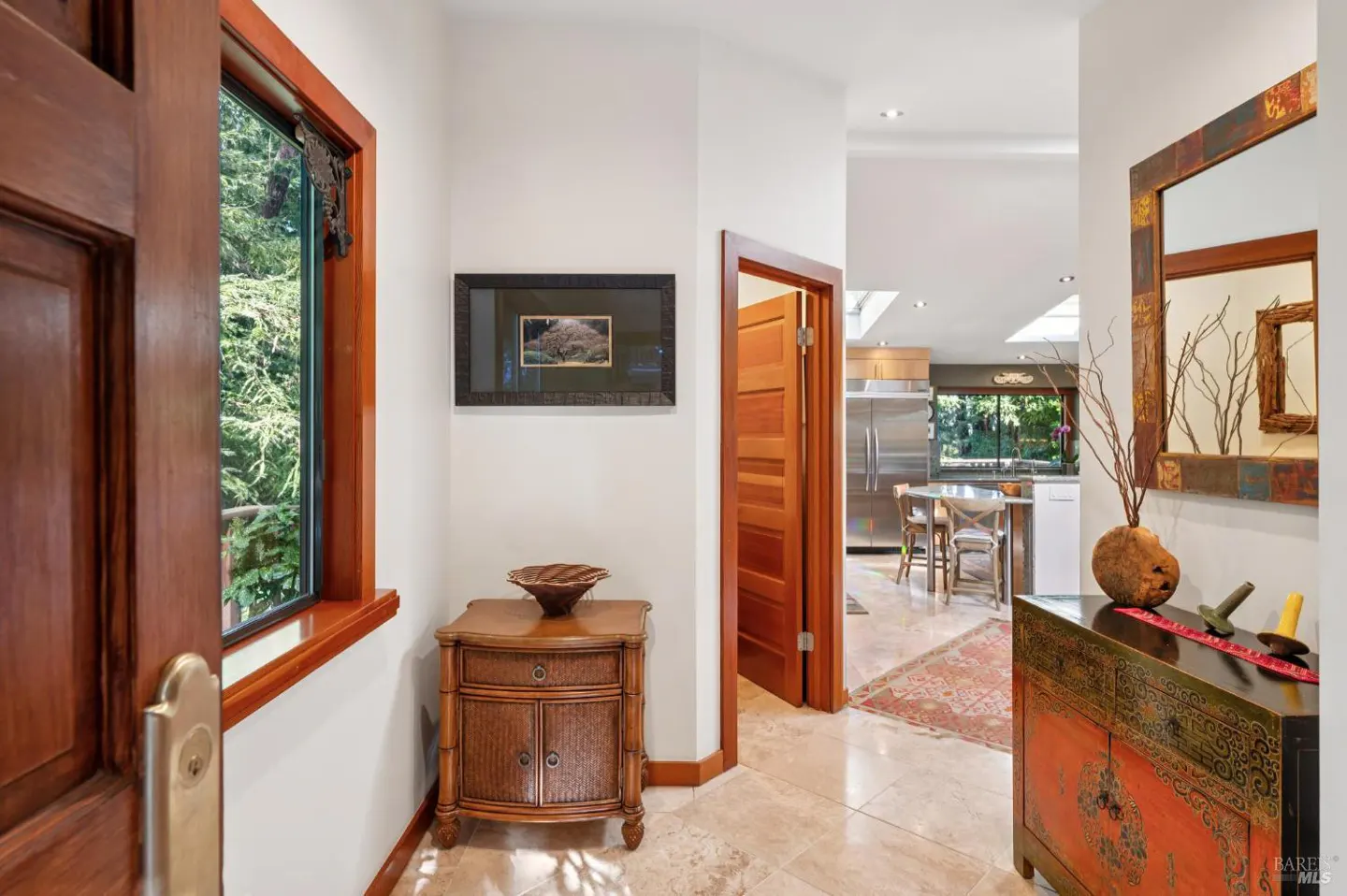 A home's entryway with an open wood door, a small table, and a view into the kitchen.