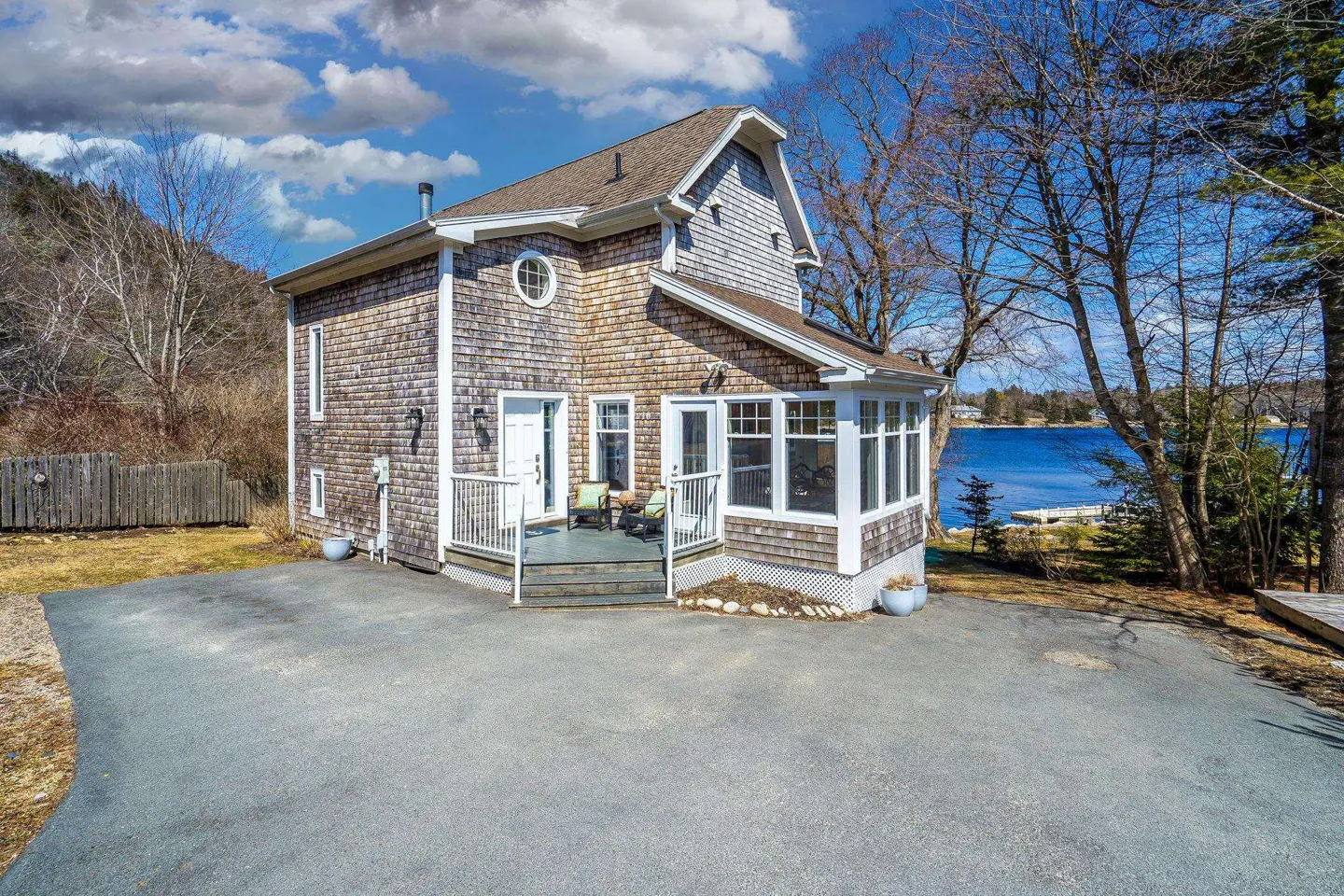 A two-story house with cedar shingles, a sunroom, and a view of a lake.