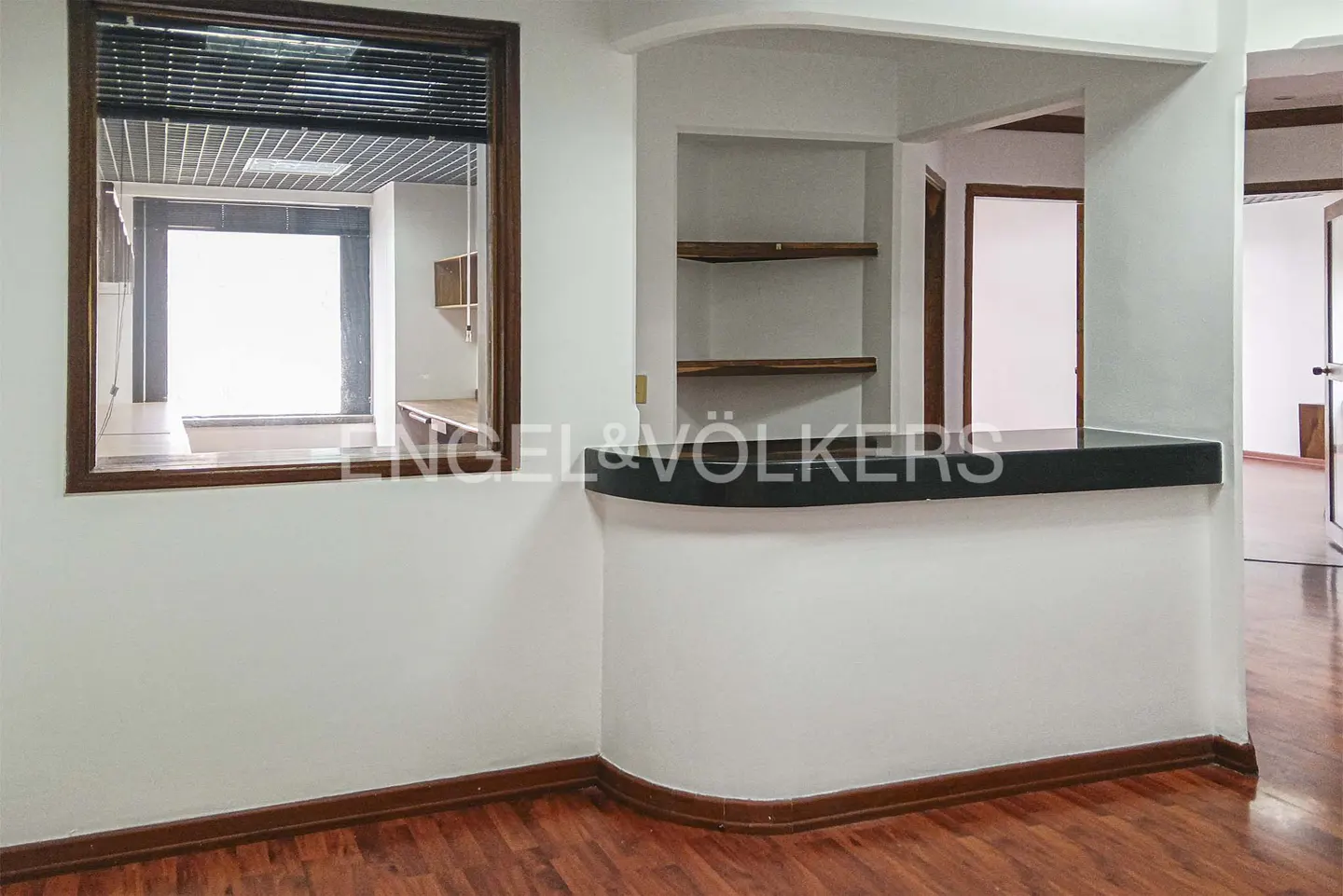 Interior view of a white room with wood floors, a window, and a bar with shelves.