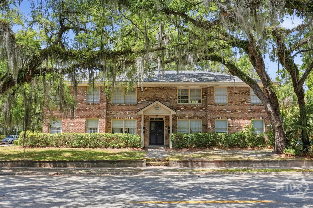 Two-story brick apartment building with a black front door and trees with Spanish moss.