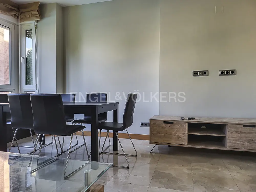 Living room with a black dining table and chairs, a wooden TV stand, and a glass coffee table.