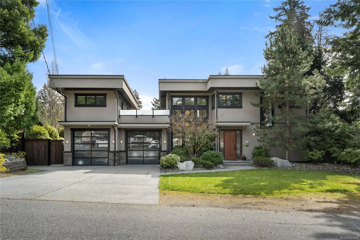 Modern two-story house with a gray exterior, black framed windows, two-car garage, and green lawn.