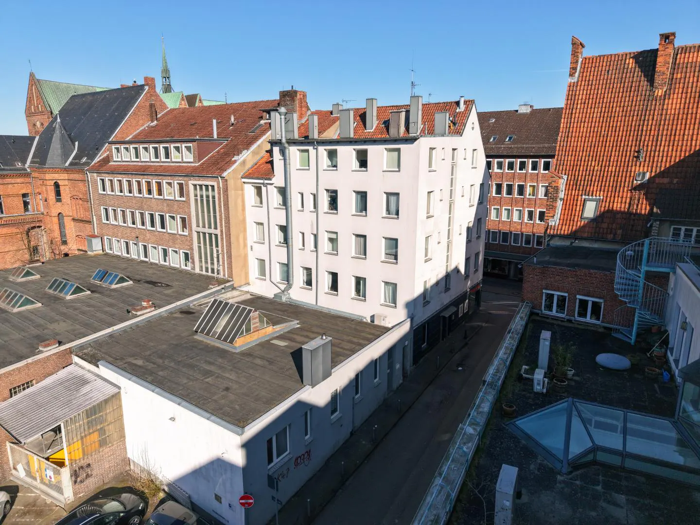 An aerial view of a city street with brick and white buildings under a clear blue sky.