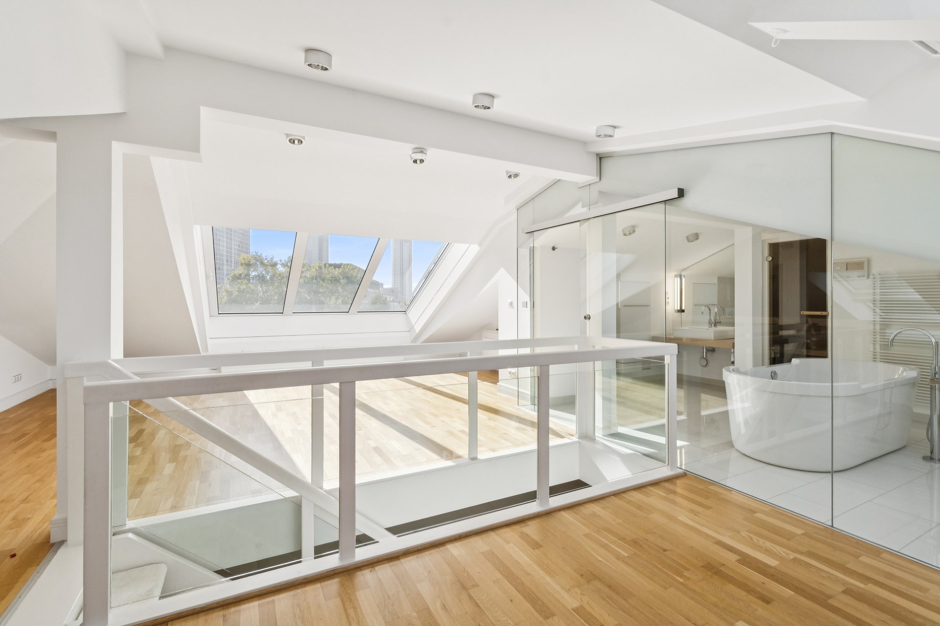 Modern loft with hardwood floors, a glass-enclosed bathroom with a soaking tub, and skylights overlooking the city. [AI-generated text]