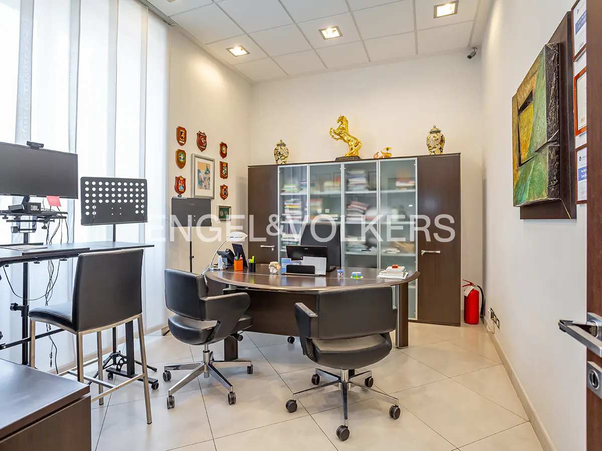 Office interior with a curved desk, black chairs, and a large cabinet with glass doors. A golden horse statue sits atop the cabinet.
