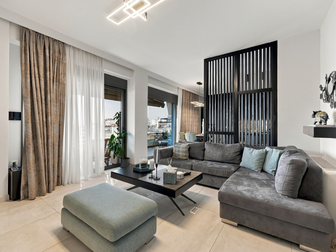 Modern living room with a grey sectional sofa, matching ottoman, coffee table, and a black slatted room divider. [AI-generated text]