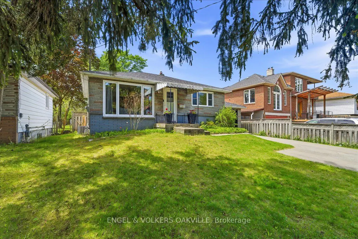A single-story house with a gray brick facade and a green lawn on a sunny day.
