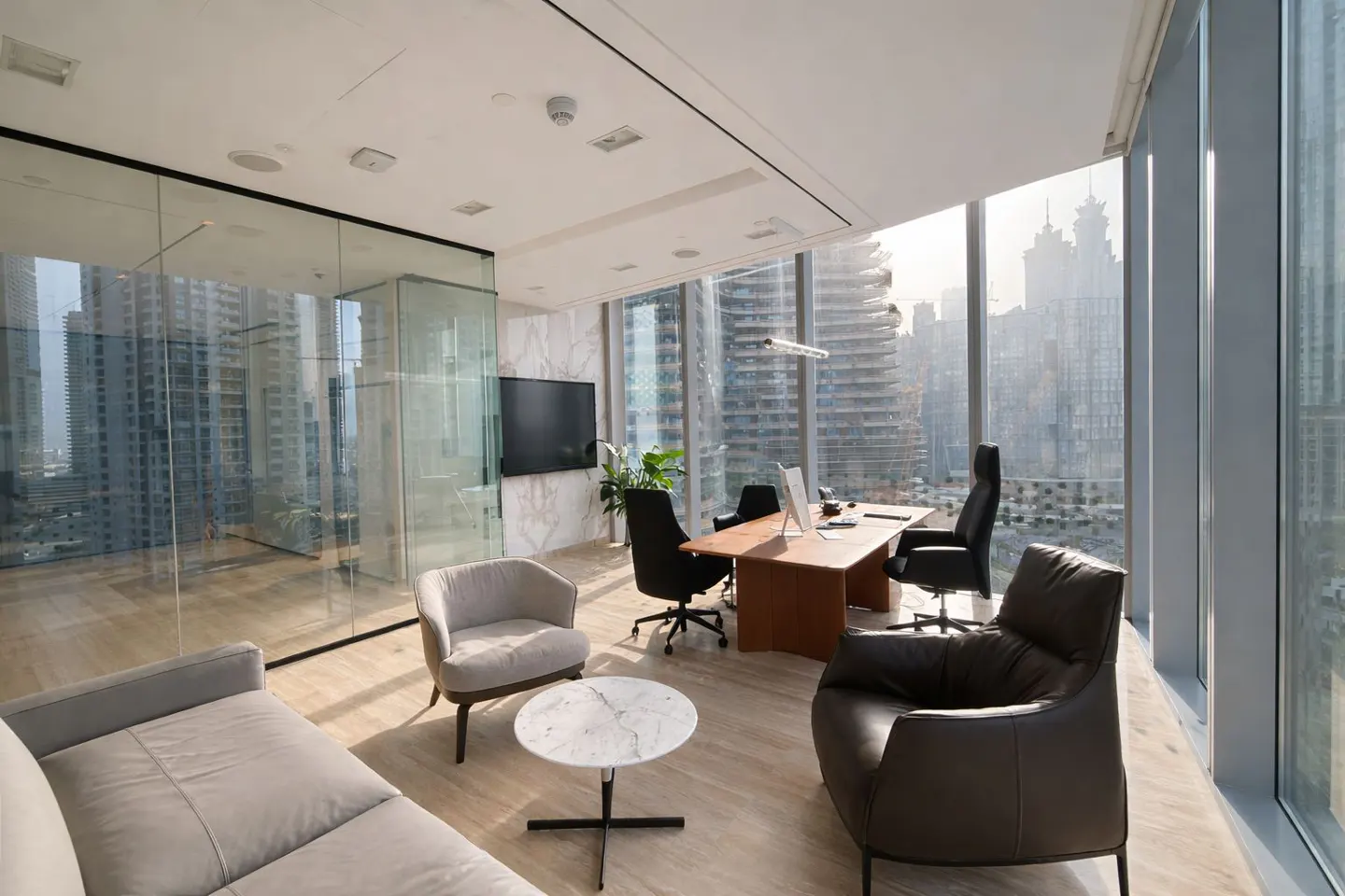 A modern office space with a desk, chairs, and a city view through large windows.